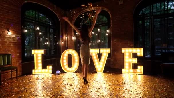 Hermosa chica posando sobre un fondo de letras brillantes — Vídeos de Stock