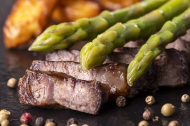 Bifteğin üstünde yeşil kuşkonmaz 