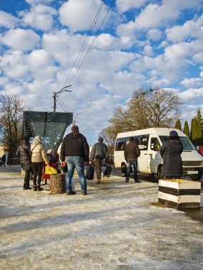 Yolcuların beklediği otobüs durağına beyaz bir minibüs geliyor.