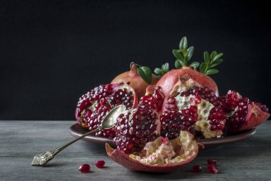 Koyu bir arka planda tatlı kaşığıyla nar ve rus.