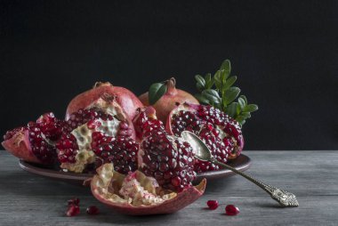 Koyu arkaplanda yapraklı nar ve tatlı sposu.