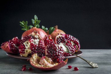 Koyu bir arka planda tatlı kaşığıyla nar ve rus.