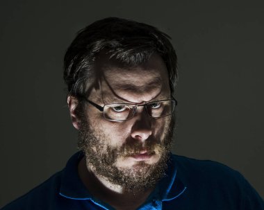 Gözlük takan adamın yüzünde çok sağlam bir bakışla kameraya bakan