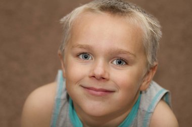 Küçük mutlu çocuk kameraya gülümsüyor.