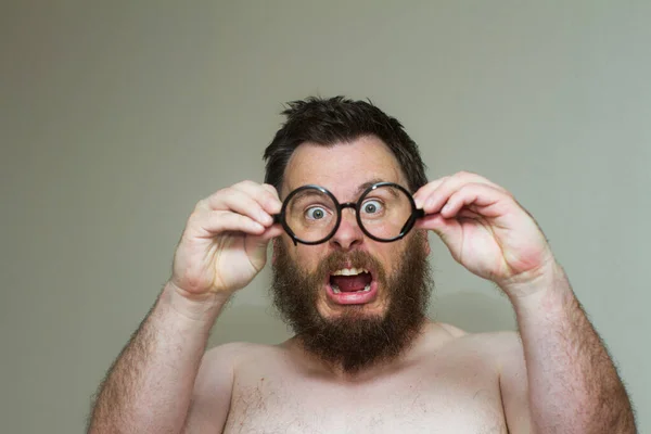 Homem nu não gostando do que ele vê depois de olhar através de seus óculos Imagem De Stock