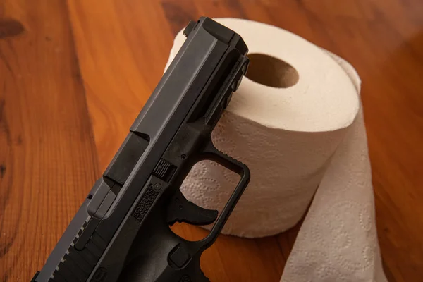 El acercamiento de la pistola que pone contra el papel higiénico — Foto de Stock