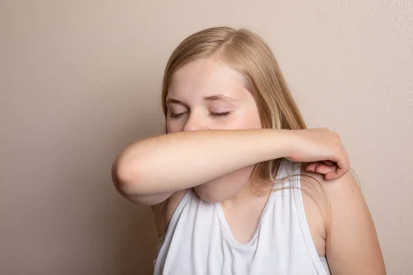 Coughing into her elbow to prevent spread of germs — Stock Photo, Image