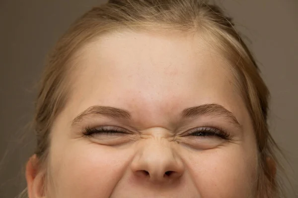 Chica joven entrecerrando los ojos mientras ríe o sonríe — Foto de Stock