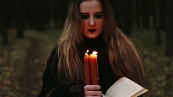 Bruxa com um livro e velas na floresta — Vídeo de Stock