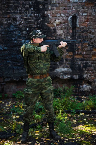 Солдат или милиционер в камуфляже с штурмовой винтовкой АК сражается в руинах — стоковое фото