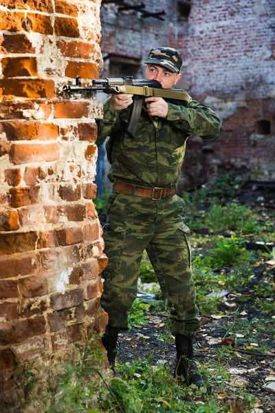 Soldado ou miliciano em camuflagem com fuzil de assalto AK lutando em ruínas — Fotografia de Stock