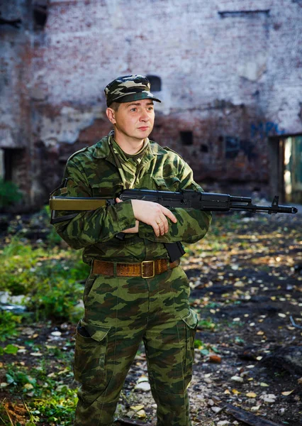 Soldaat of burgerwacht in camouflage met aanval geweer Ak-74 poseren in ruïnes — Stockfoto