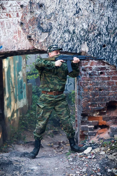 Soldaat of burgerwacht in camouflage met aanval geweer Ak gevechten in ruïnes — Stockfoto