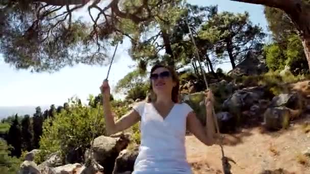 Eine fröhliche Frau mit Sonnenbrille ist auf einer Schaukel. Sie ist glücklich und genießt es. junger Erwachsener lächelt in Kamera und lacht — Stockvideo