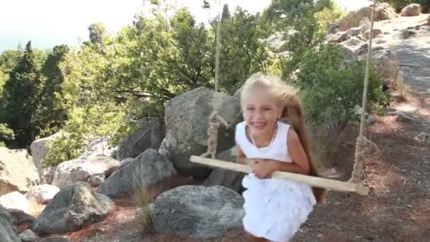 Retrato de una chica. Se ríe en un columpio. Niño mirando a la cámara — Vídeo de stock