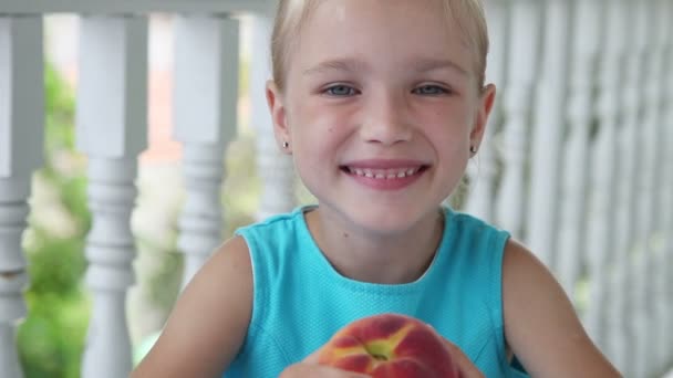 Großaufnahme Porträt Kind. Mädchen dreht den Pfirsich in der Hand — Stockvideo
