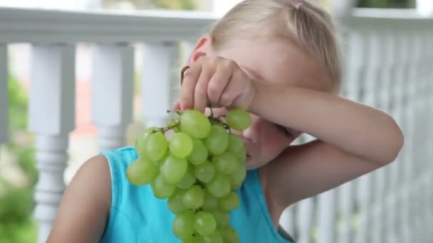 Bambino con uva che guarda la macchina fotografica e sorride. Ok, si vede. Pollici in su — Video Stock