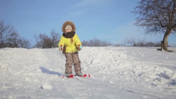 Щаслива мила маленька дівчинка катається на сніговому пагорбі на лижах — стокове відео