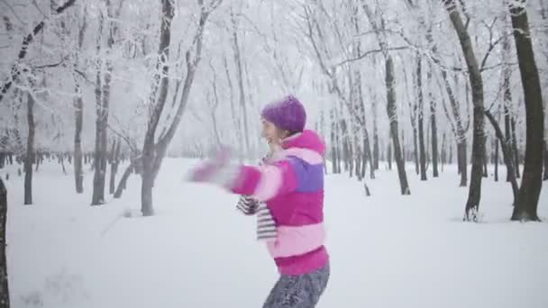 Portret leuke jonge vrouw spelen met sneeuw. Ze is spinnen in de sneeuw — Stockvideo