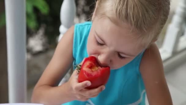 Une fille qui mange une tomate rouge. Gros plan portrait de jeune fille — Video