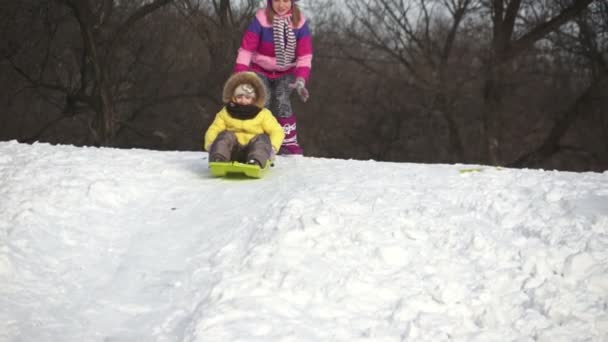 Criança montando em um trenó pelas colinas — Vídeo de Stock