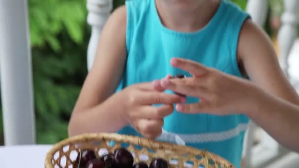 Kicsi lány, elhelyezés egy nagy cseresznye a szájába, és eszik meg — Stock videók