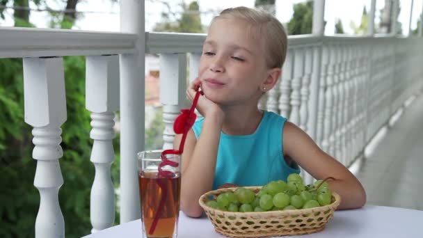Красивая девушка ест виноград и смотрит в камеру — стоковое видео
