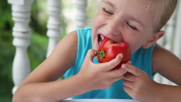 Ребёнок ест помидоры. Портрет крупного плана. Девушка смотрит в камеру и улыбается — стоковое видео