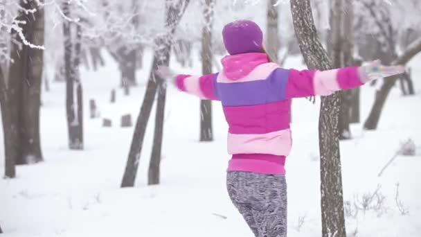 Portret leuke jonge vrouw spelen met sneeuw. Ze is glimlachend en spinnen in de sneeuw — Stockvideo
