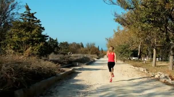 Mujer rubia joven corriendo en el parque — Vídeo de stock