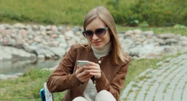 Joven mujer adulta usando el teléfono celular y mirando a la cámara — Vídeo de stock