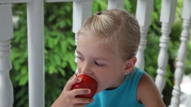 Menina comendo um tomate vermelho grande e sorrindo para a câmera. Polegares para cima. Está bem. — Vídeo de Stock