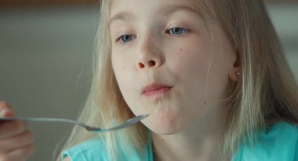 Крупним планом обличчя дівчини, що їсть полуницю з вершками і дивиться на камеру — стокове відео