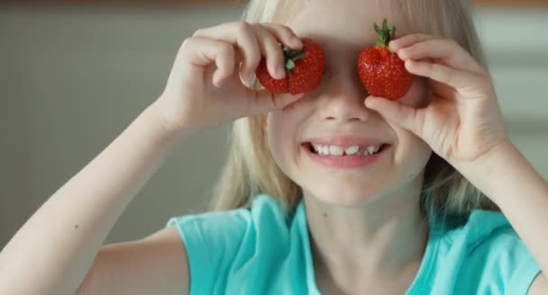 Chica riendo jugando con dos fresas. Retrato de primer plano — Vídeo de stock