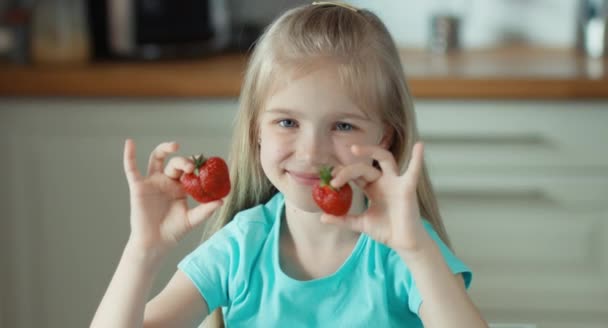 Nettes Mädchen mit zwei Erdbeeren tupft und schaut in die Kamera — Stockvideo