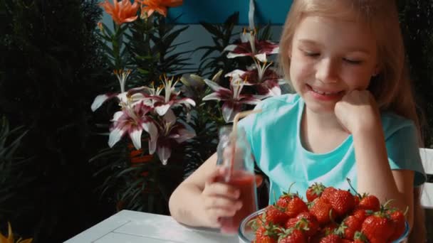 Chica bebiendo jugo de fresa y comiendo fresas. Ampliación — Vídeos de Stock