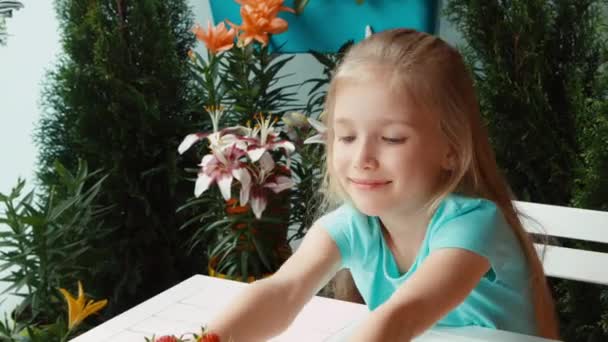 Girl with a big plate of strawberries looking at camera and smiling. Child sniffing strawberries. Thumbs up. Ok. Zooming — Stock Video