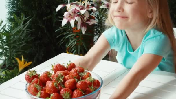 Mädchen mit einem großen Teller Erdbeeren blickt in die Kamera und lächelt. Daumen hoch. Ok. zoomen — Stockvideo