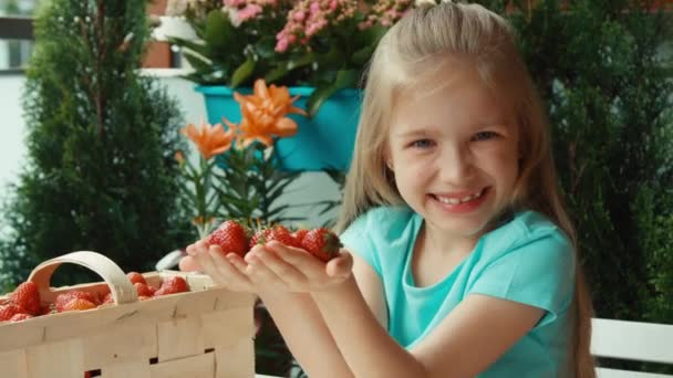 Dziewczyna, podziwiając truskawka. Dziecko z garść truskawek, patrząc na kamery. Proffers owoców do widzów. Powiększanie — Wideo stockowe