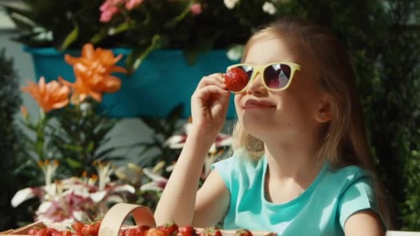 Mädchen, das Erdbeeren isst und in die Kamera schaut. Daumen hoch. Ok. zoomen — Stockvideo