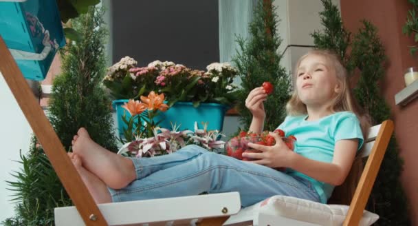 Κορίτσι, κρατώντας ένα τεράστιο πιάτο με φράουλες και τρώει με ευχαρίστηση — Αρχείο Βίντεο
