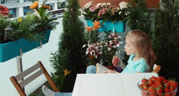 Girl reading a book and drinking strawberry juice — Stock Video