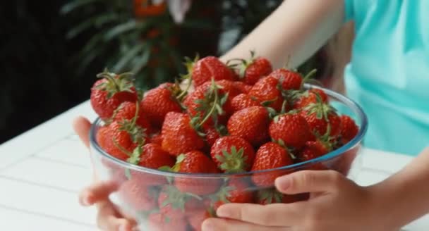 Girl hugging a big plate of strawberries looking at camera and smiling. Slow — Stock Video