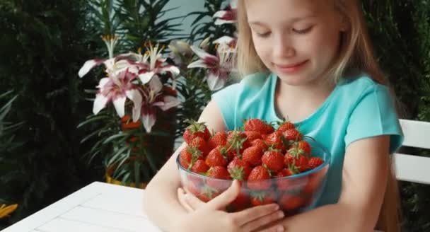 Chica abrazando un gran plato de fresas mirando a la cámara y sonriendo. Pulgar hacia arriba. Ok. — Vídeos de Stock