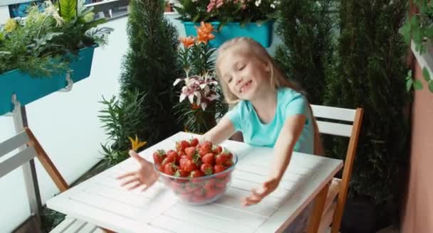 Menina com um grande prato de morangos olhando para a câmera e sorrindo — Vídeo de Stock