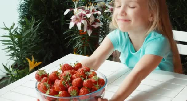 一大盘子草莓看着相机，微笑着的女孩。大拇指。还行 — 图库视频影像