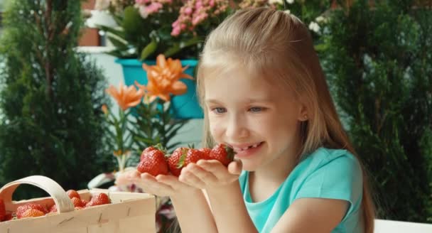 Nahaufnahme Porträt Kind Mädchen mit einer Handvoll Erdbeeren — Stockvideo