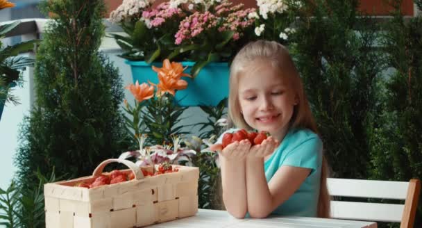 Nahaufnahme Porträt Mädchen mit einer Handvoll Erdbeeren und Beeren schnüffeln. Angebotene Beeren — Stockvideo