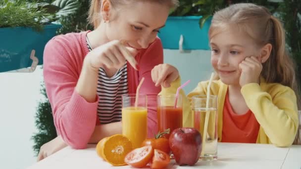 Moeder en dochter gezond vruchtensap drinken en camera te kijken. Duimen omhoog. OK. Zoomen — Stockvideo