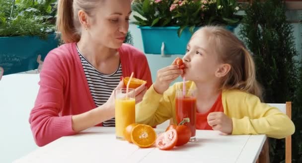 Familie isst Tomaten und Orangen und lacht in die Kamera — Stockvideo